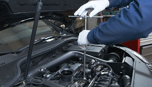 man with white gloves unscrewing an engine cap